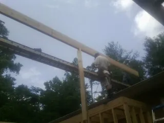 Carpenter setting a ridge beam over a new addition frame — Ice Dam Removal by Roofing Brothers in Wapanucka