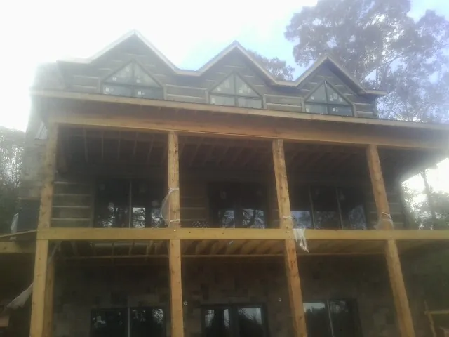 Dormers and porch framing on a large log home under construction — Roof Coating work by our crew in Wapanucka