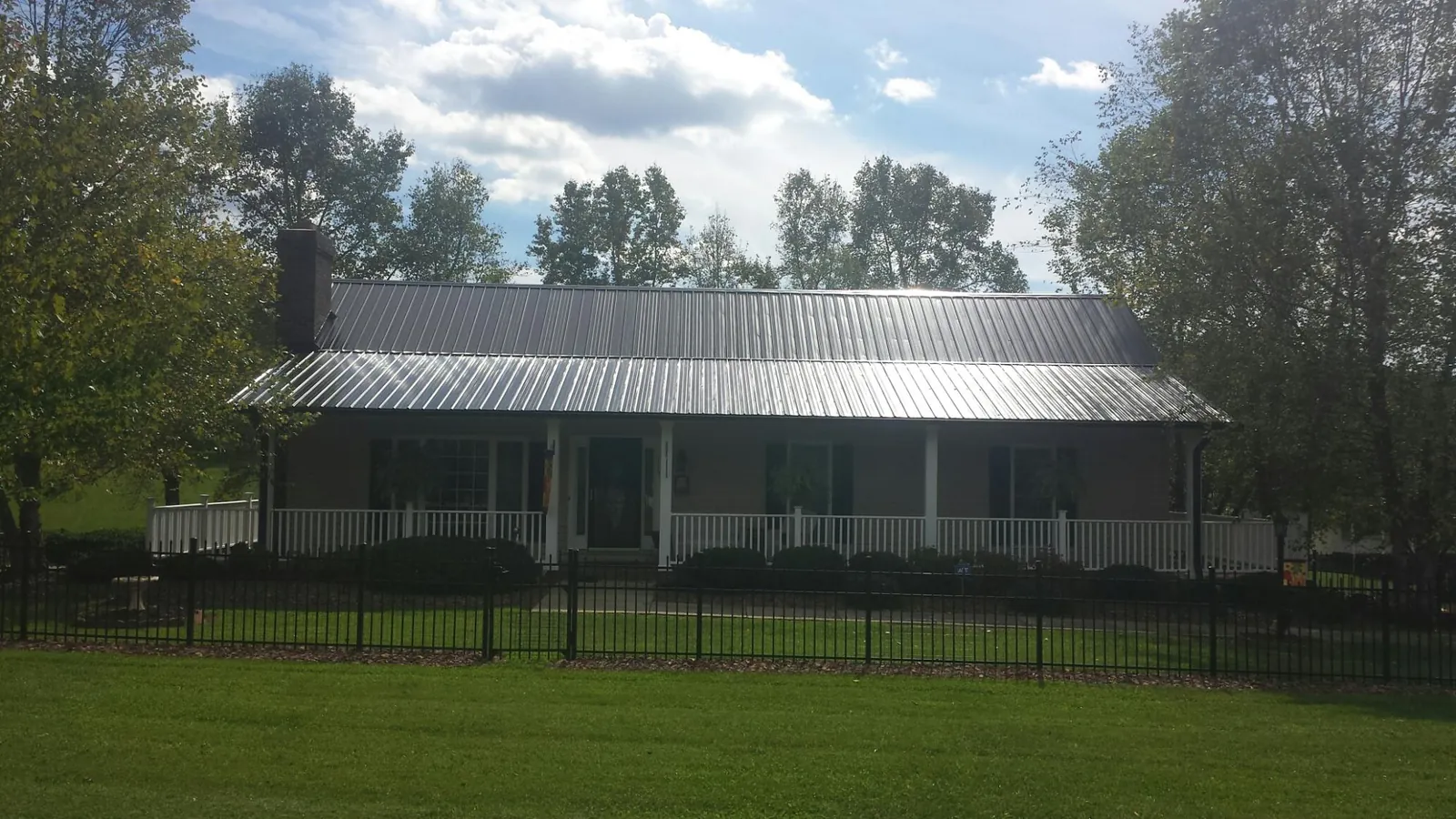 Gray metal roof on a brick ranch with a full width front porch — Gutter Guard Installation work by our crew in Wapanucka