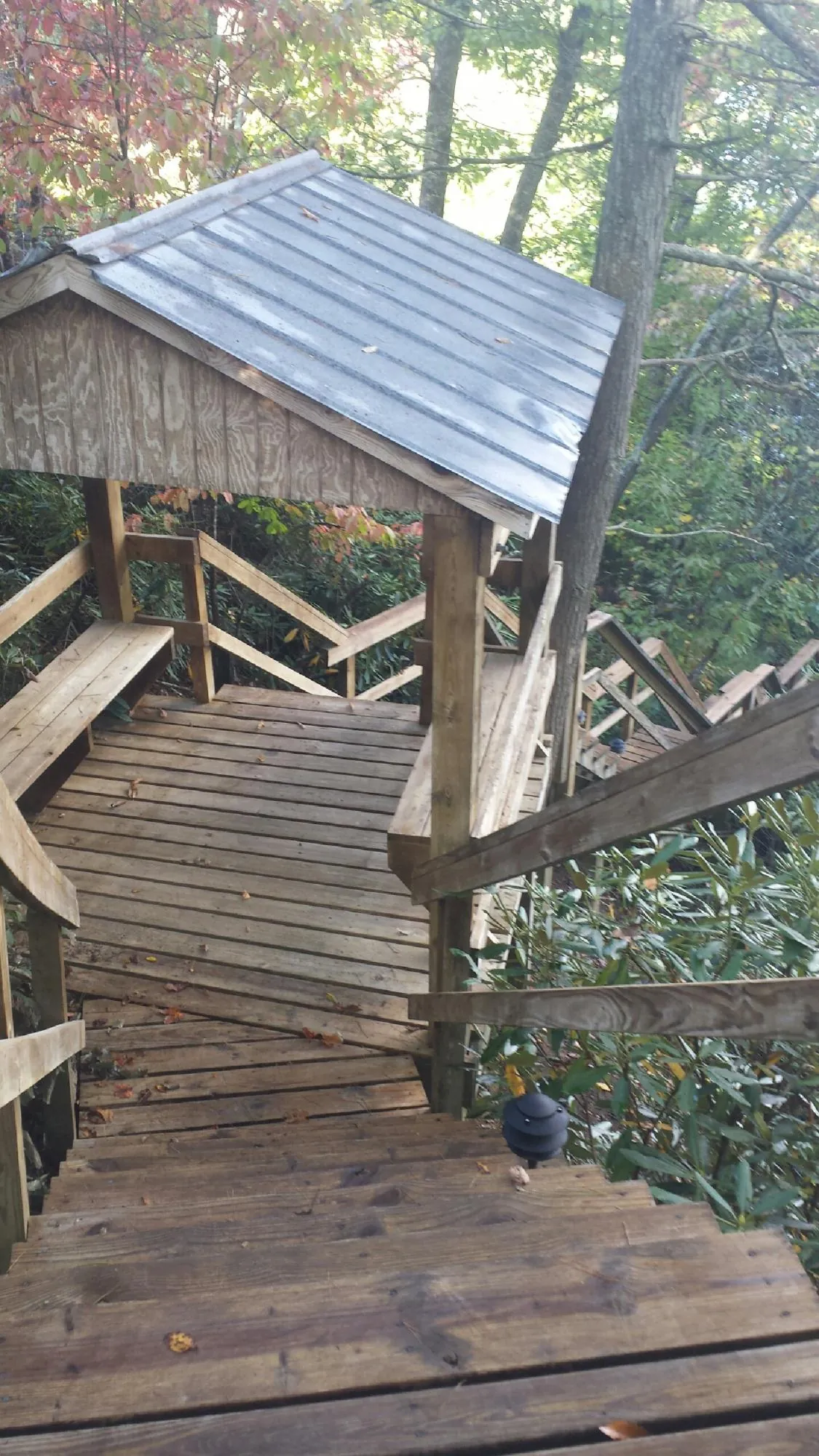 Metal roofed shelter over wooden steps on a wooded walkway — Skylight Repair & Installation work by our crew in Wapanucka