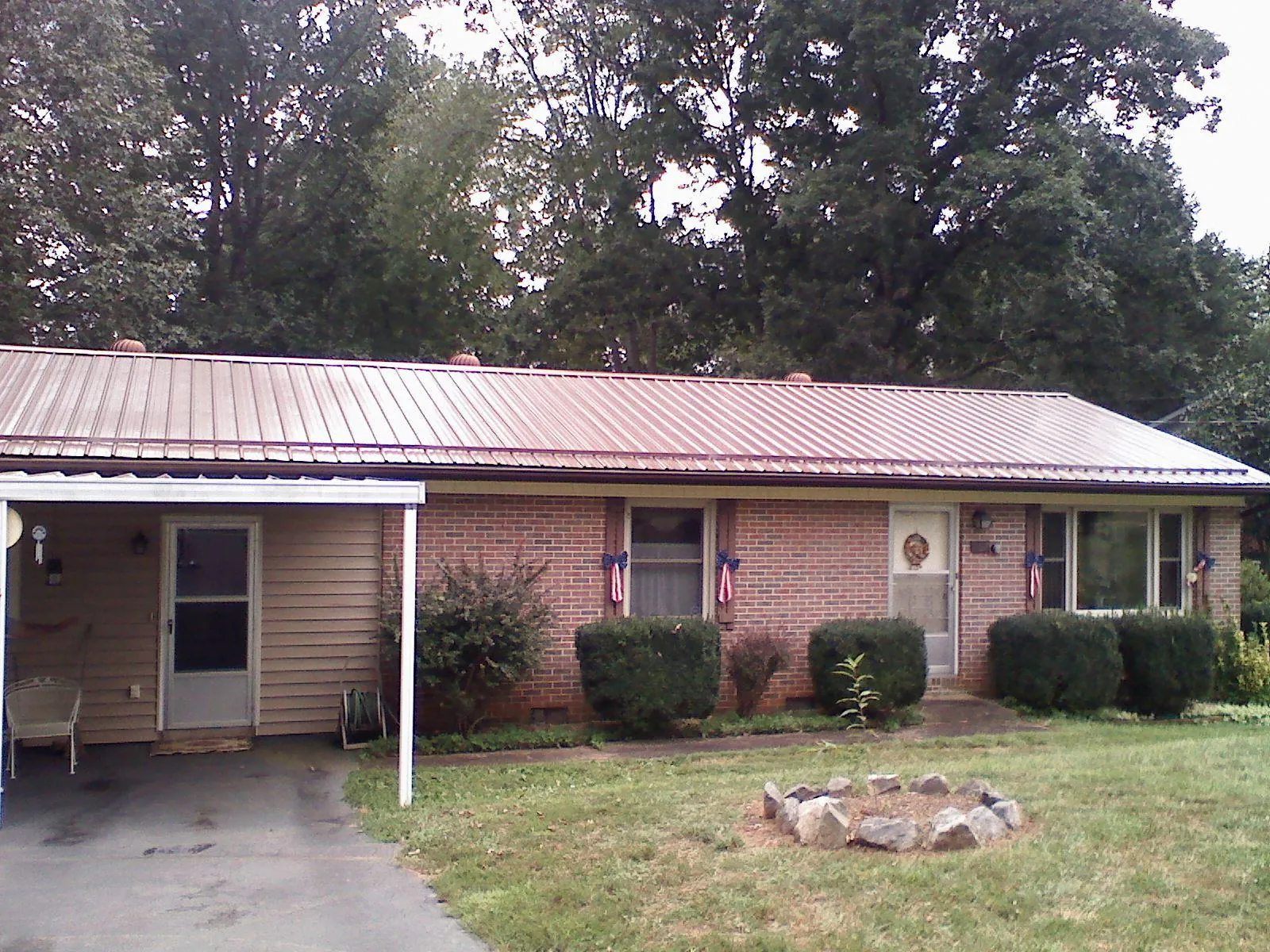 Bronze metal roof and carport on a brick ranch home — Roof Repair work by our crew in Wapanucka