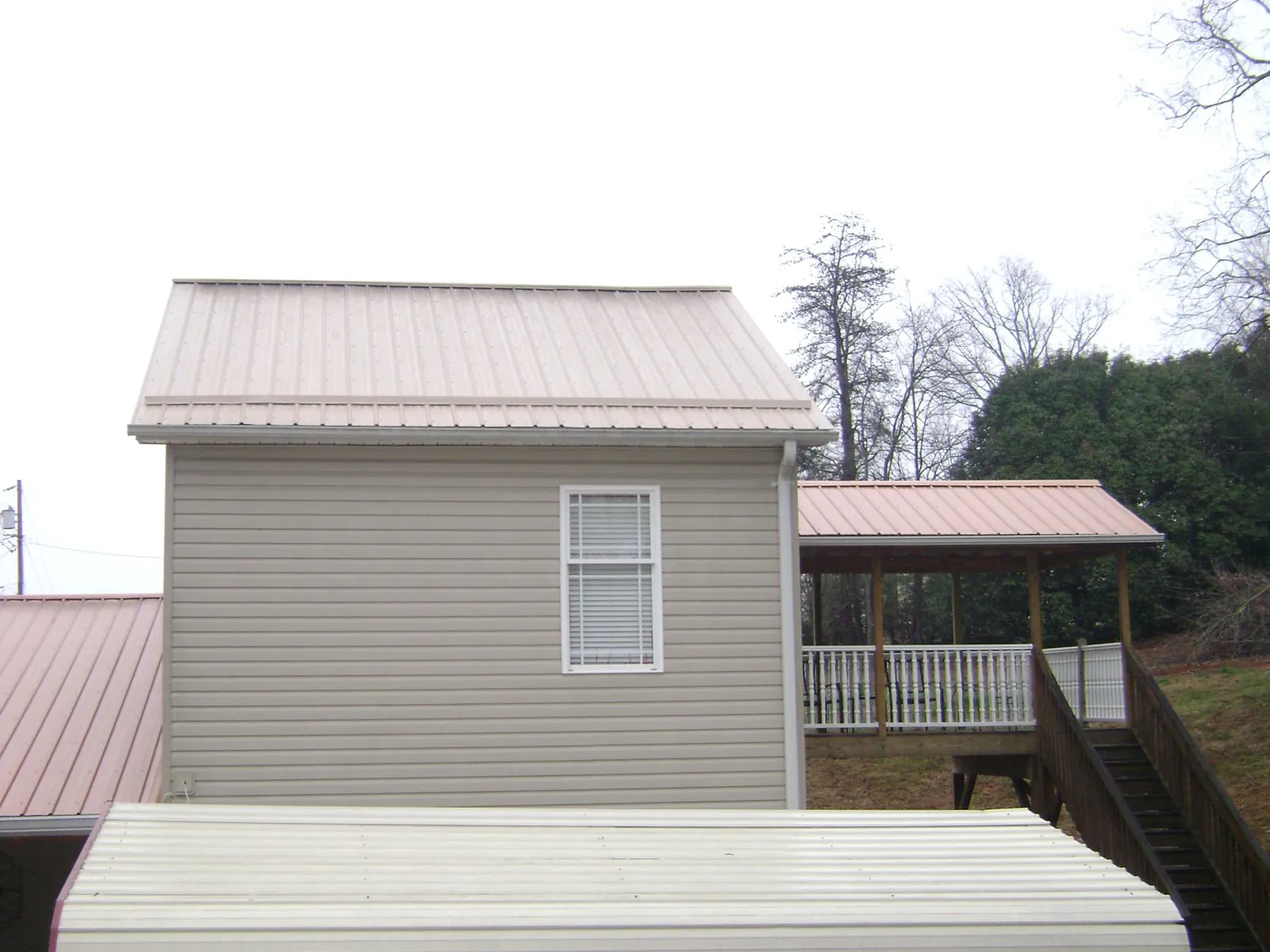 Tan metal roofs on a two story addition and attached porch, from a Roof Replacement job in Wapanucka