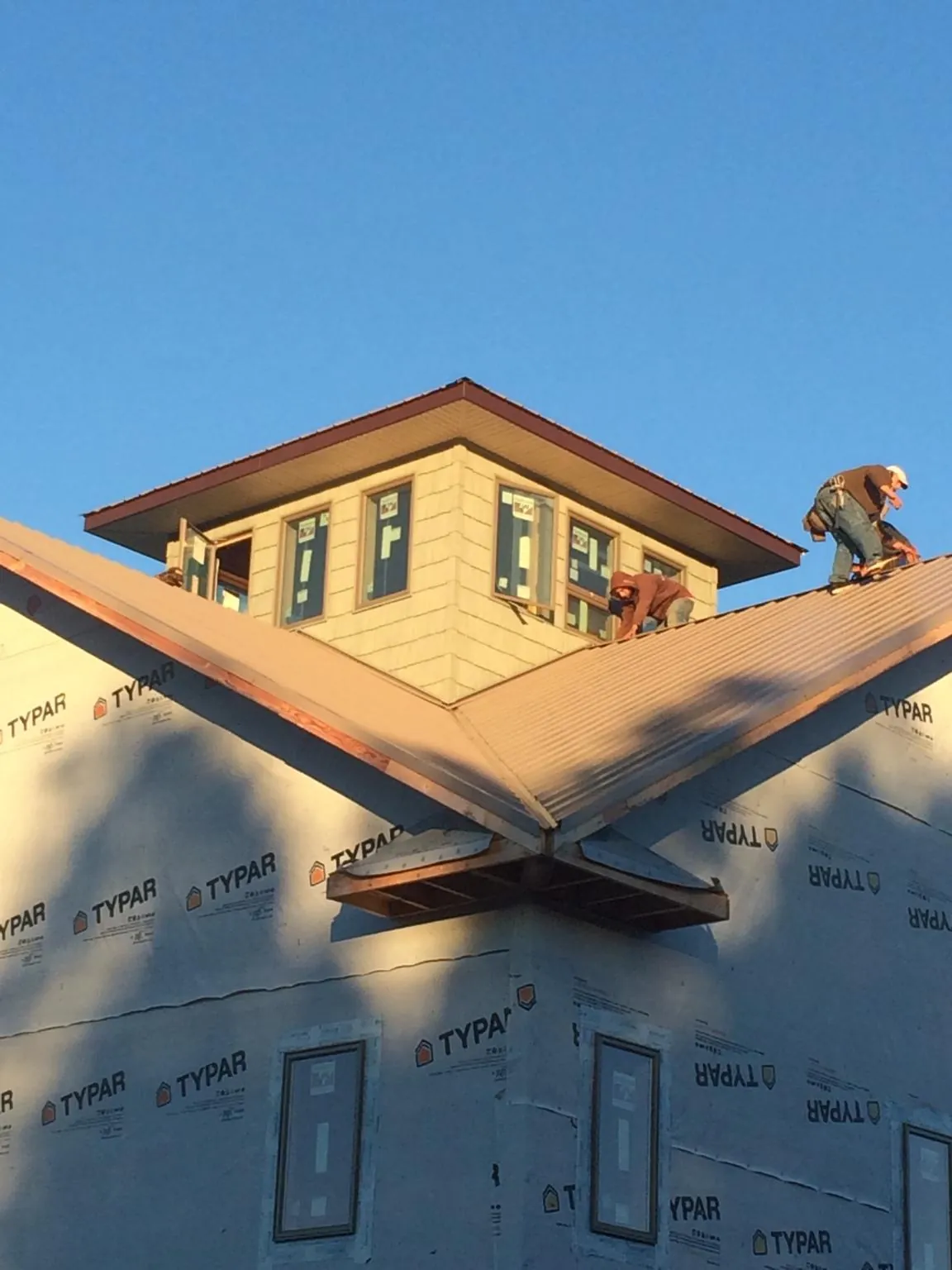 Roofers working around a rooftop cupola on a new metal roof at sunset — Roof Waterproofing in Wapanucka by Roofing Brothers